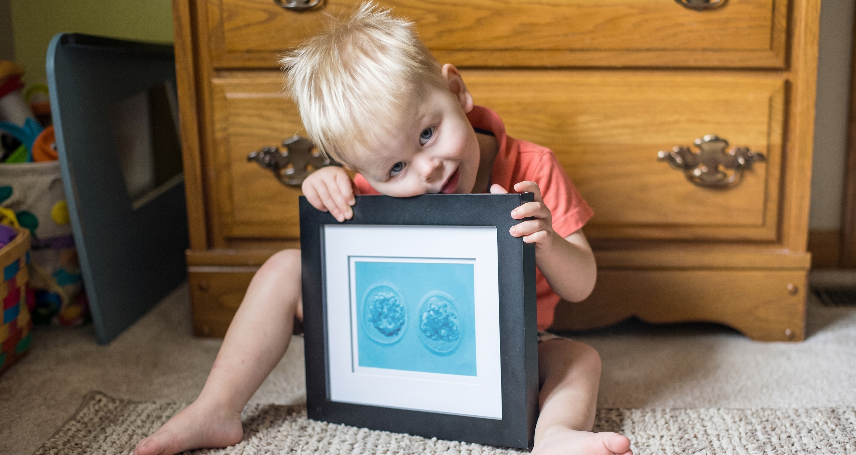 A little boy holding a framed photo of his embryo