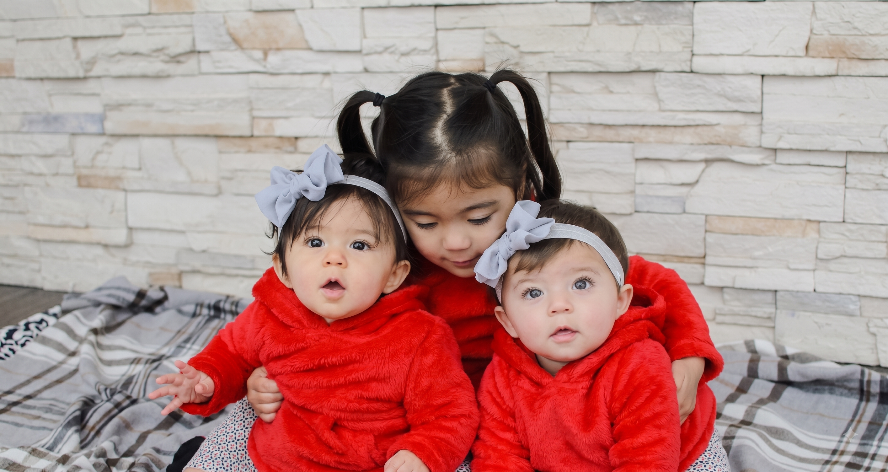 Three young sisters in red, cuddled together