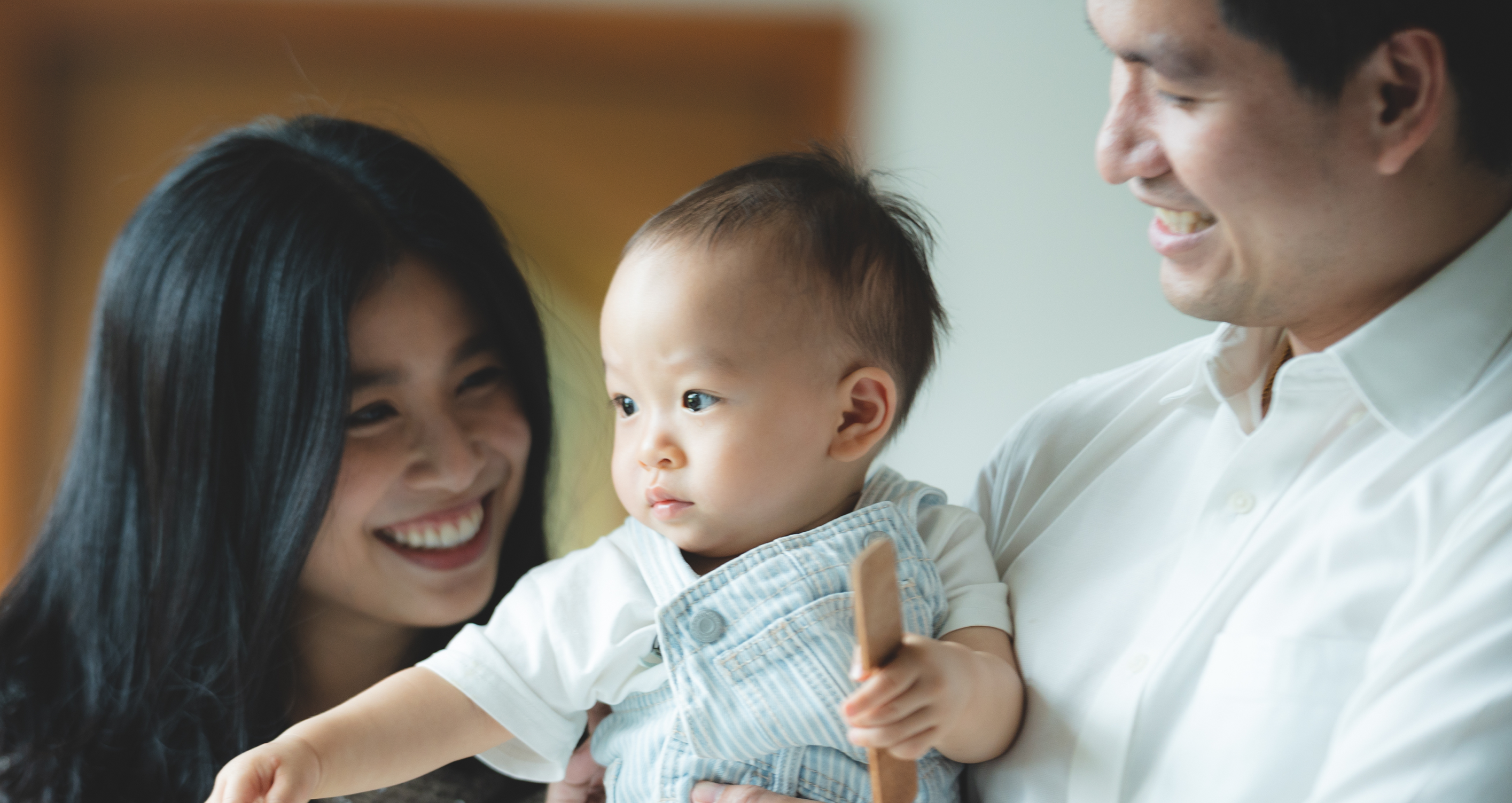 A mother and father smiling with their baby