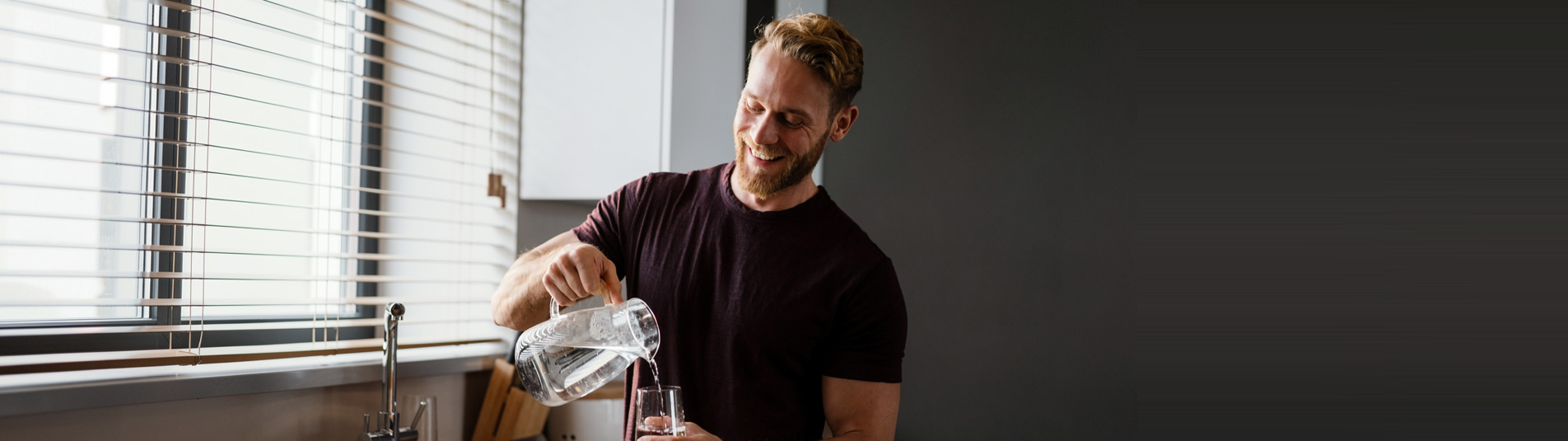 Man pouring a glass of filtered water in his kitchen
